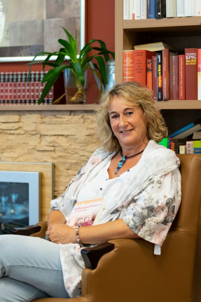 lächelnde Frau vor Bücherregal